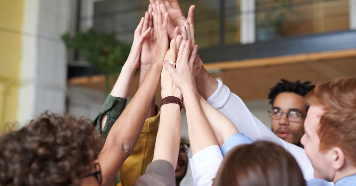 A group of diverse professionals celebrating teamwork with a high-five indoors.